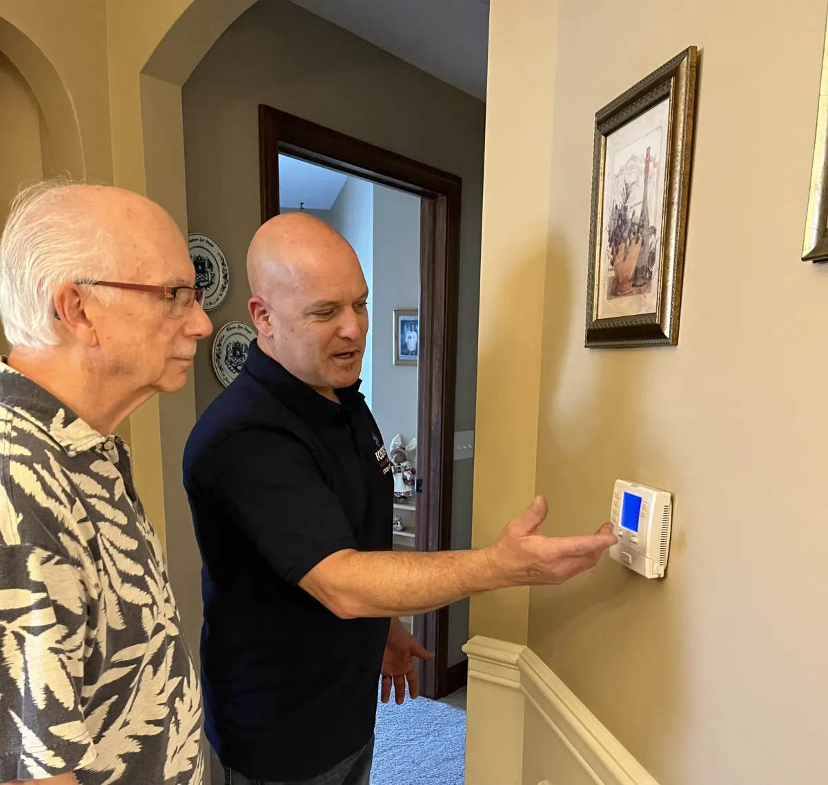 Ryan from Foster's Heating & Air showing a homeowner his thermostat